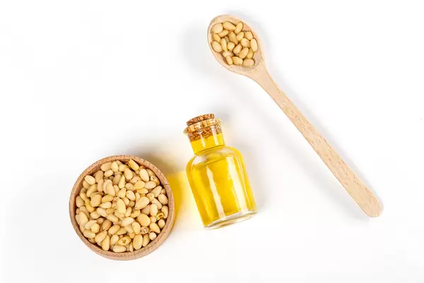 Top view, pine nut oil in bottle with pine nuts in wooden spoon and bowl