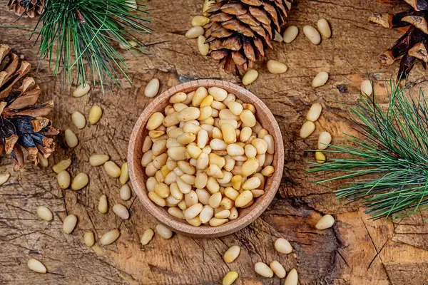 Top view, pine nuts with cones and pine branches on an old wooden background