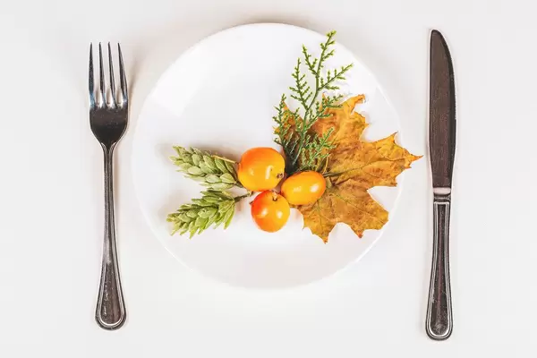 Top view, plate with knife and fork with autumn decor