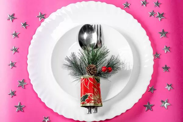 Top view plates with spoon and fork on a pink background with silvery stars (Flip 2019)
