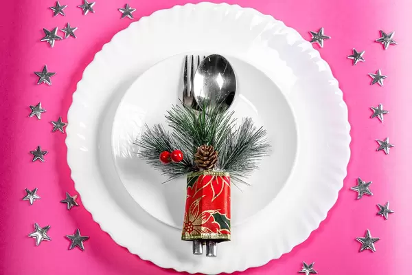 Top view plates with spoon and fork on a pink background with silvery stars