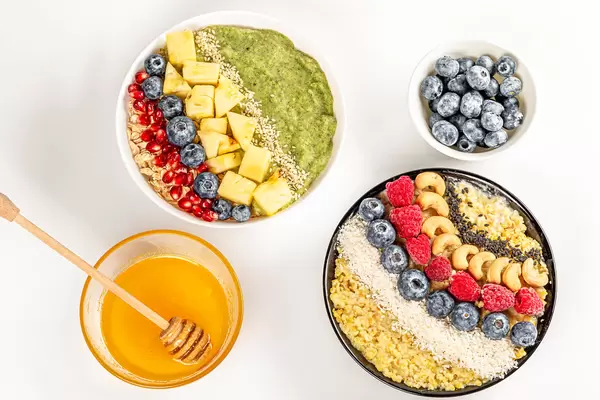 Top view, porridge with fresh berries, fruits, nuts, seeds and honey