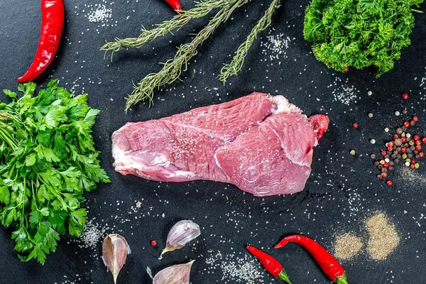 Top view raw pork with spices and herbs on black background