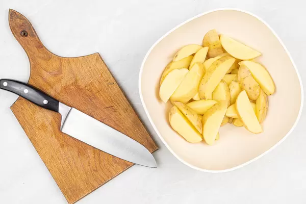 Top view Raw Sliced Potatoes with cutting board and knife
