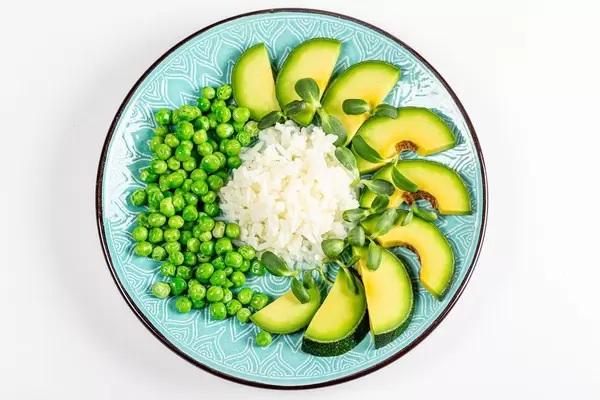 Top view rice with avocado, green peas and sunflower microgreen on a white background