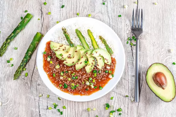 Top view. Rice with tomato-Apple sauce, flax seeds and vegetables on a wooden background
