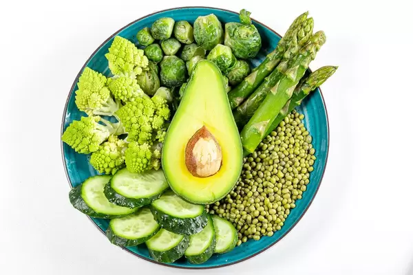 Top view, romanesco cabbage, cucumber, avocado, Brussels sprouts, asparagus and green peas on a white background