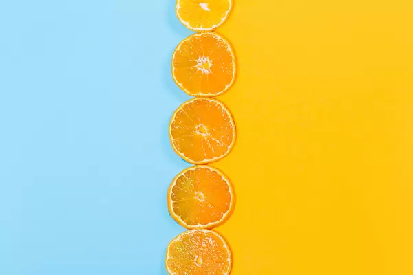 Top view, round pieces of tangerine on orange and blue background