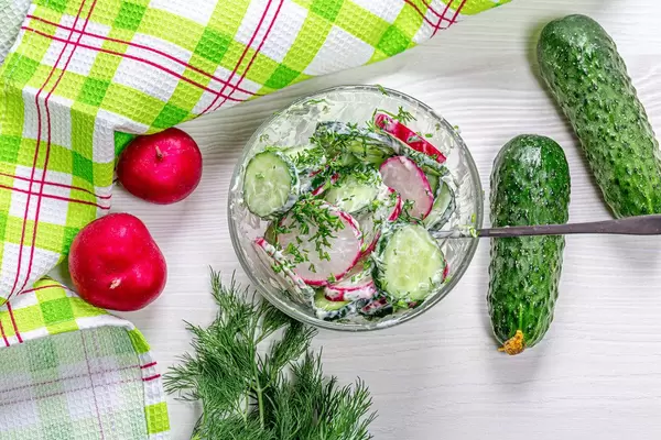 Top view salad with radish, cucumber and dill in a glass bowl
