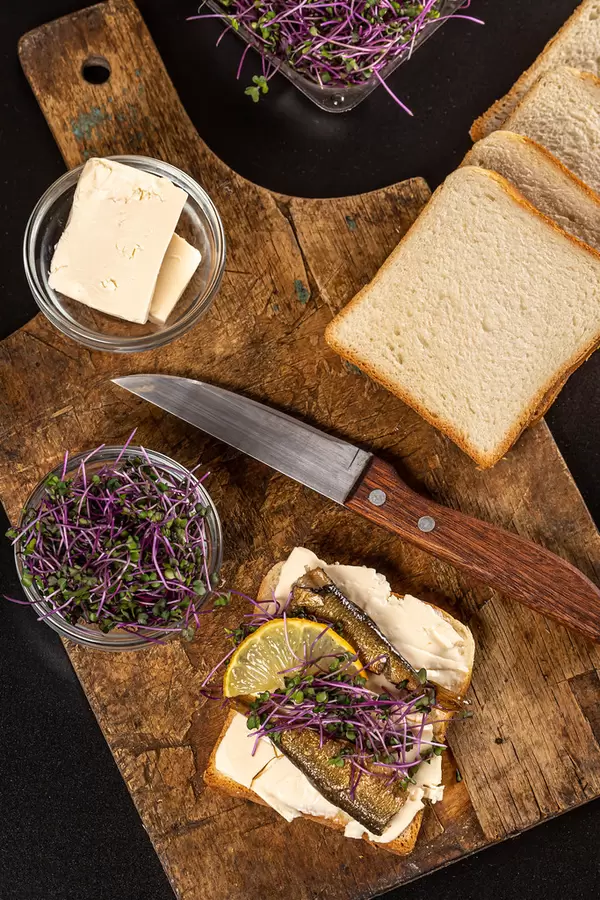 Top view, sandwich with sprats, microgreens of cabbage and a slice of lemon
