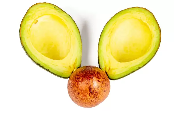 Top view, seed and two halves of ripe avocado