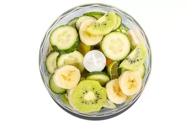 Top view, slices of banana, cucumber, kiwi, apple, spinach, lime in a blender