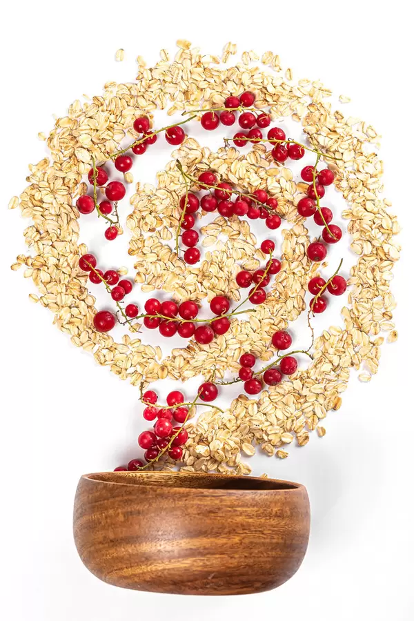 Top view, spiral with oatmeal and red currant berries with wooden bowl