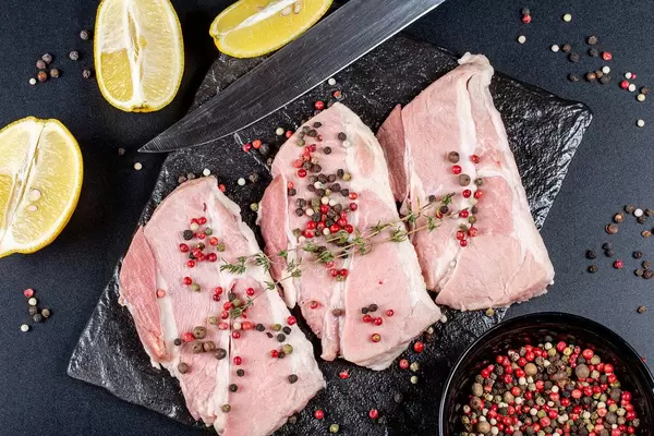 Top view, steaks with spices, lemon slices and a knife on a dark background (Flip 2020)
