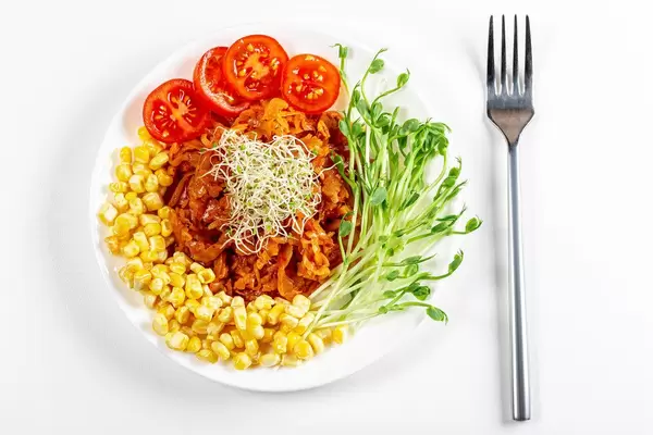 Top view, stewed cabbage with micro greenery and vegetables on a white background