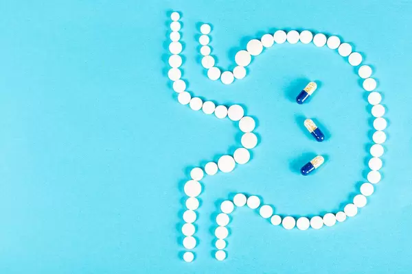 Top view, stomach from pills on blue and three capsules inside