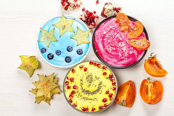 Top view three bowls of oatmeal with fresh fruit, berries and seeds on a white wooden background (Flip 2019)