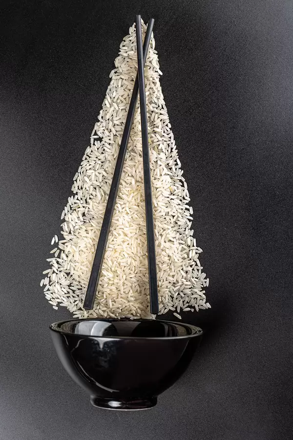 Top view, uncooked rice with bowl and chopsticks on black background