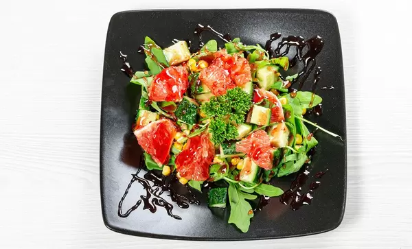 Top view vegetarian salad with arugula, vegetables and grapefruit slices on a black plate (Flip 2019)