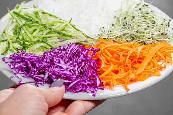 Top-view vegetarisches Mittagessen mit Reis und Gemüse in einer Hand einer Frau