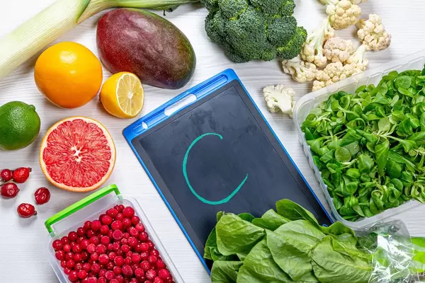 Top-view von Obst und Gemüse - Kräuter und Beeren auf einem weißen Holzhintergrund symbolisieren die an Vitamin C reichhaltigen Lebensmittel