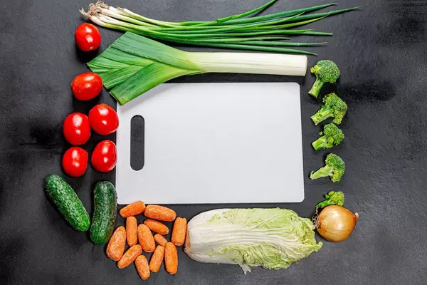 Top view white kitchen Board in collapse of fresh vegetables on black background
