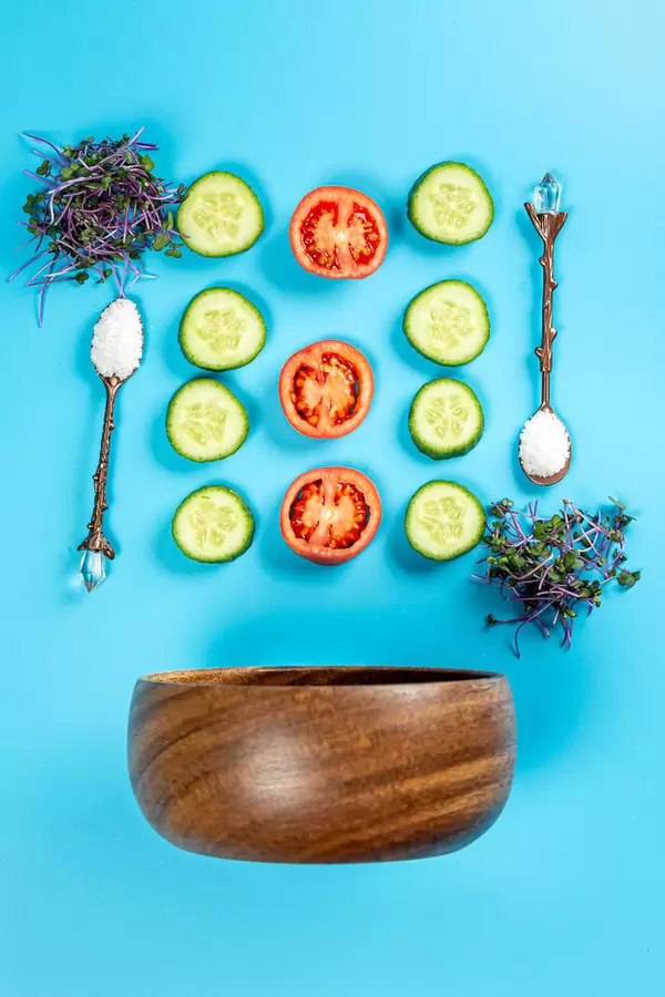 Top view, wooden bowl with ingredients for salad on blue background