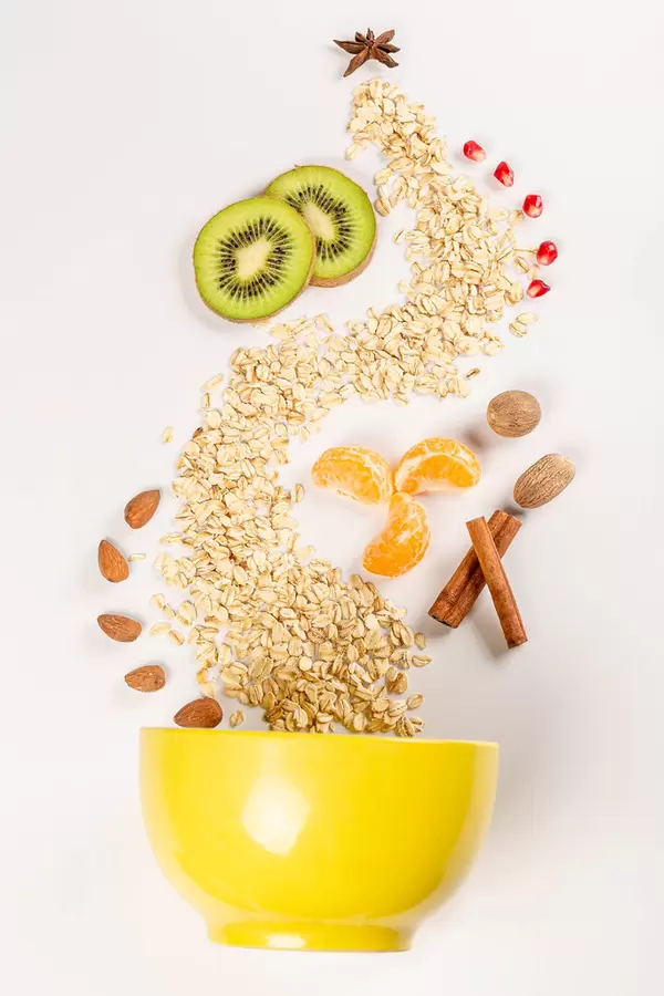 Top view, yellow bowl with scattered ingredients for making healthy breakfast