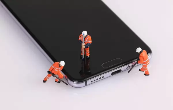 Topview of miniature workers repairing smartphone