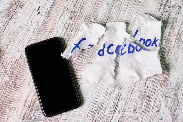 Torn napkin with Facebook text on it and mobile phone