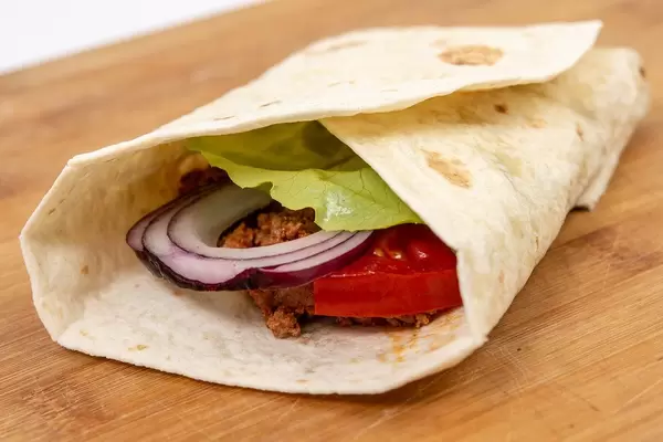 Tortilla with Minced meat Tomato and Lettuce on the wooden table (Flip 2019)