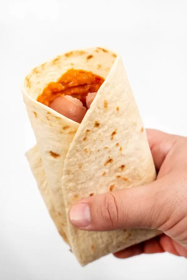 Tortilla with Sausages in the hand above white background (Flip 2020)