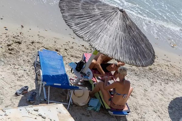 Tourist couple under a straw parasol at the beach
