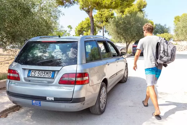 Tourist im Sommerurlaub geht auf ein Mietwagen zu