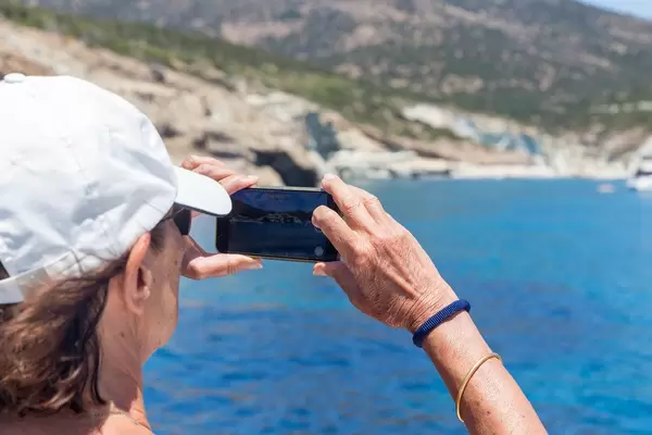 Tourist in Urlaub auf Milos, Griechenland macht ein Foto von der Küste mit seinem Smartphone