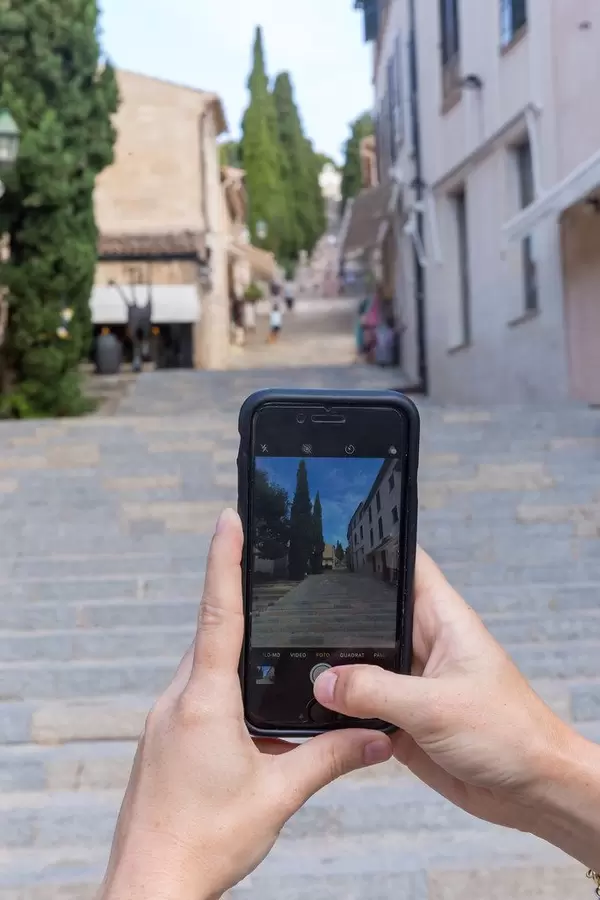Tourist mit iPhone in den Händen fotografiert die Treppe mit 365 Stufen bei Pollença, Mallorca
