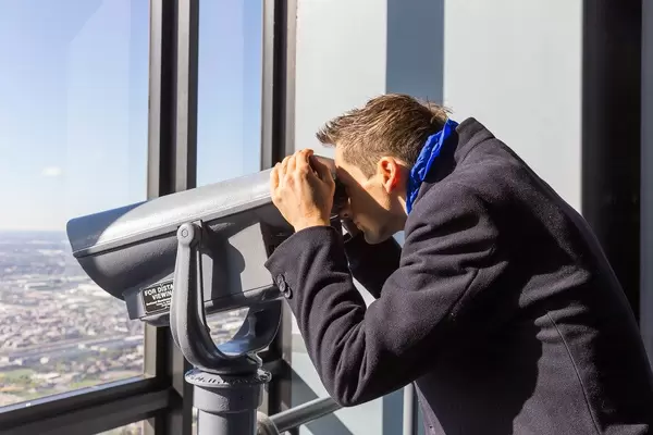 Tourist uses a coin-operated binocular to get a better view of the sights of Chicago