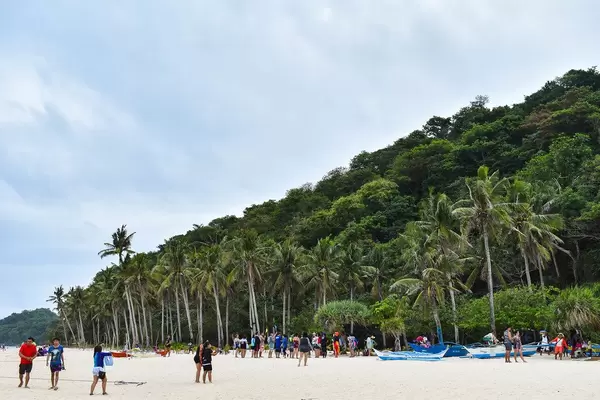 Touristen genießen den paradiesischen Puka Beach auf Boracay mit schneeweißem Sand und Palmen