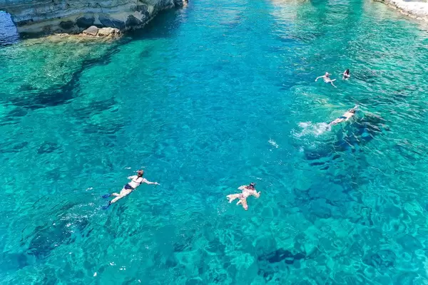 Touristen schnorcheln in den türkisen Gewässern von Kleftiko während des Bootsausflugs um Milos