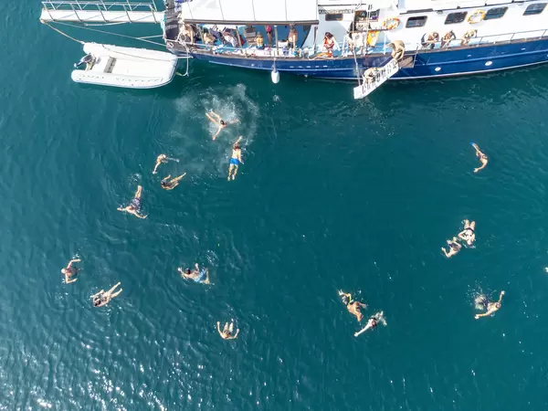 Touristen schwimmen in den Gewässern von Peristera während eines Segelbootausflugs. Drohnenaufnahme
