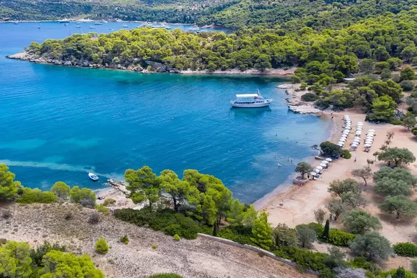 Touristenboot fährt in die Bucht des Paralia Zogeria Strandes auf der Insel Spetses, Griechenland