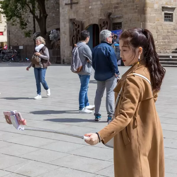 Touristin mit Selfiestange am Plaça Nova nahe der Kathedrale La Seu in der Altstadt von Barcelona, Spanien