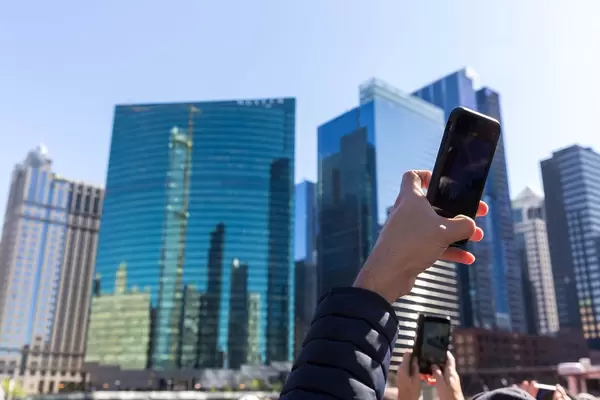 Tourists on a sightseeing boat tour on the Chicago River use their smartphones to take a photo of the 333 Wacker Drive skyscraper
