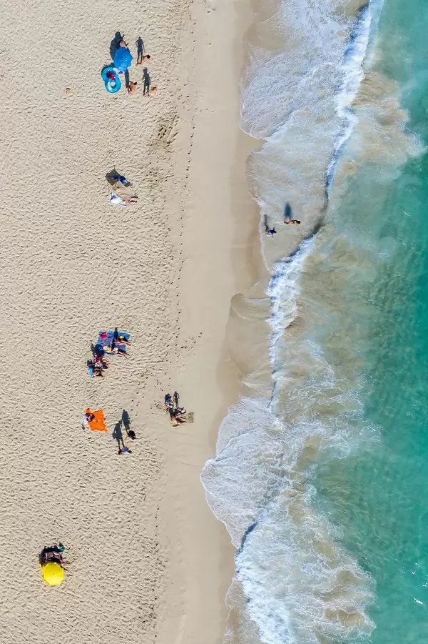 Tourists sunbathing by the shore in Mallorca in summer 2020. Cala Mesquida, drone photo