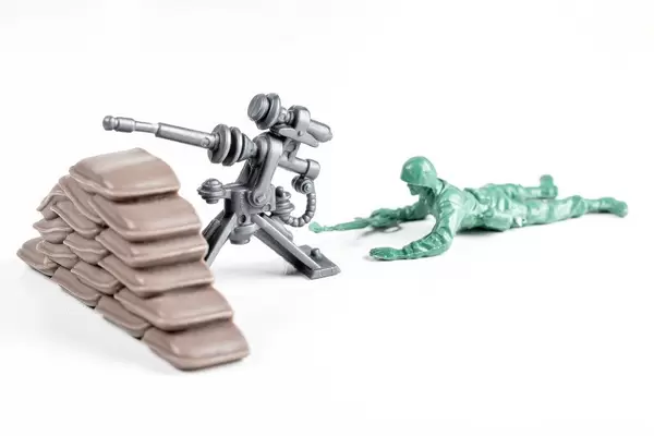 Toy soldier with a machine gun on white. War concept