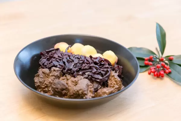 Traditional beef stew with apple beetroot salad and potato dumplings with a twig on a wooden table