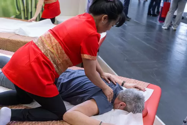 Traditional Thai massage given to a woman at Fibo fitness trade show