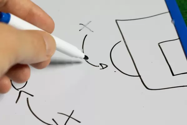 Trainer erklärt die Taktik anhand einer Zeichnung auf einem Whiteboard