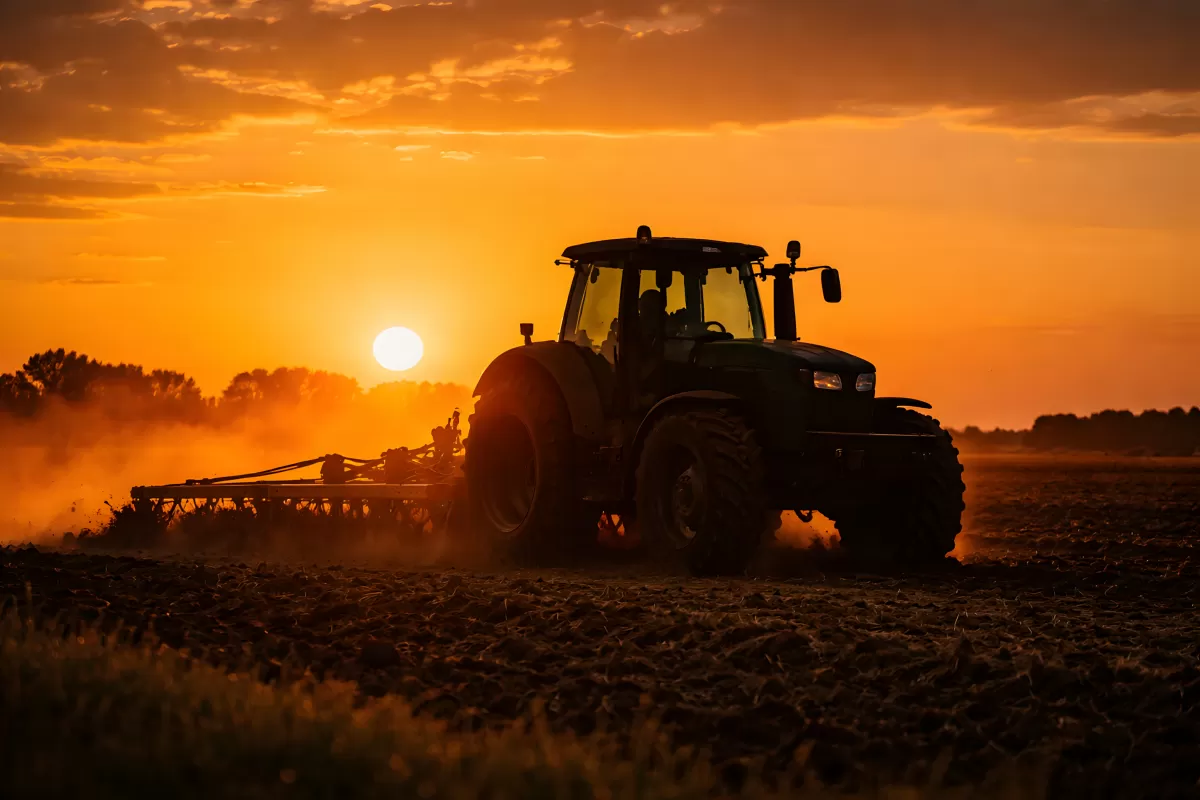Traktor pflügt Feld bei dramatischem Sonnenuntergang