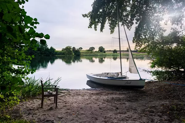 Tranquil and relaxing scene with a wooden chair on the shore next to a boat